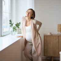 Healthcare, treatment. Young pregnant woman feeling sudden pain in her back. Future mom suffering from backpain. High quality photo