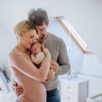 Parents holding their newborn son in their home.